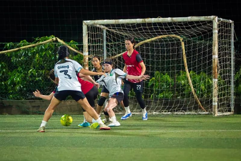 Jugadoras disputan la pelota frente al arco en un partido nocturno